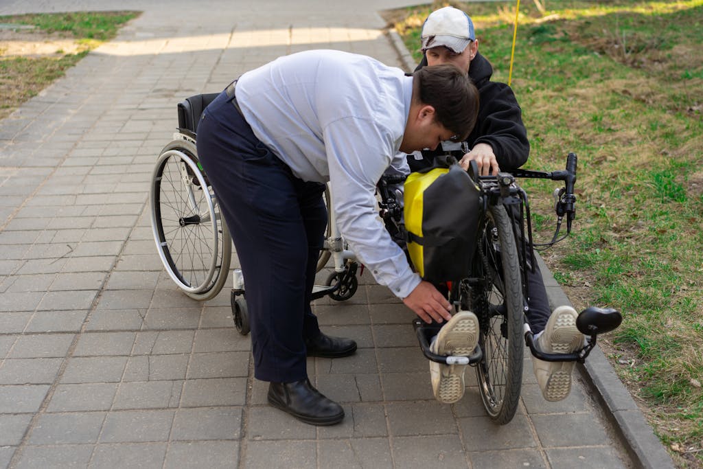 Man assists another with electric wheelchair outdoors, highlighting support and mobility.